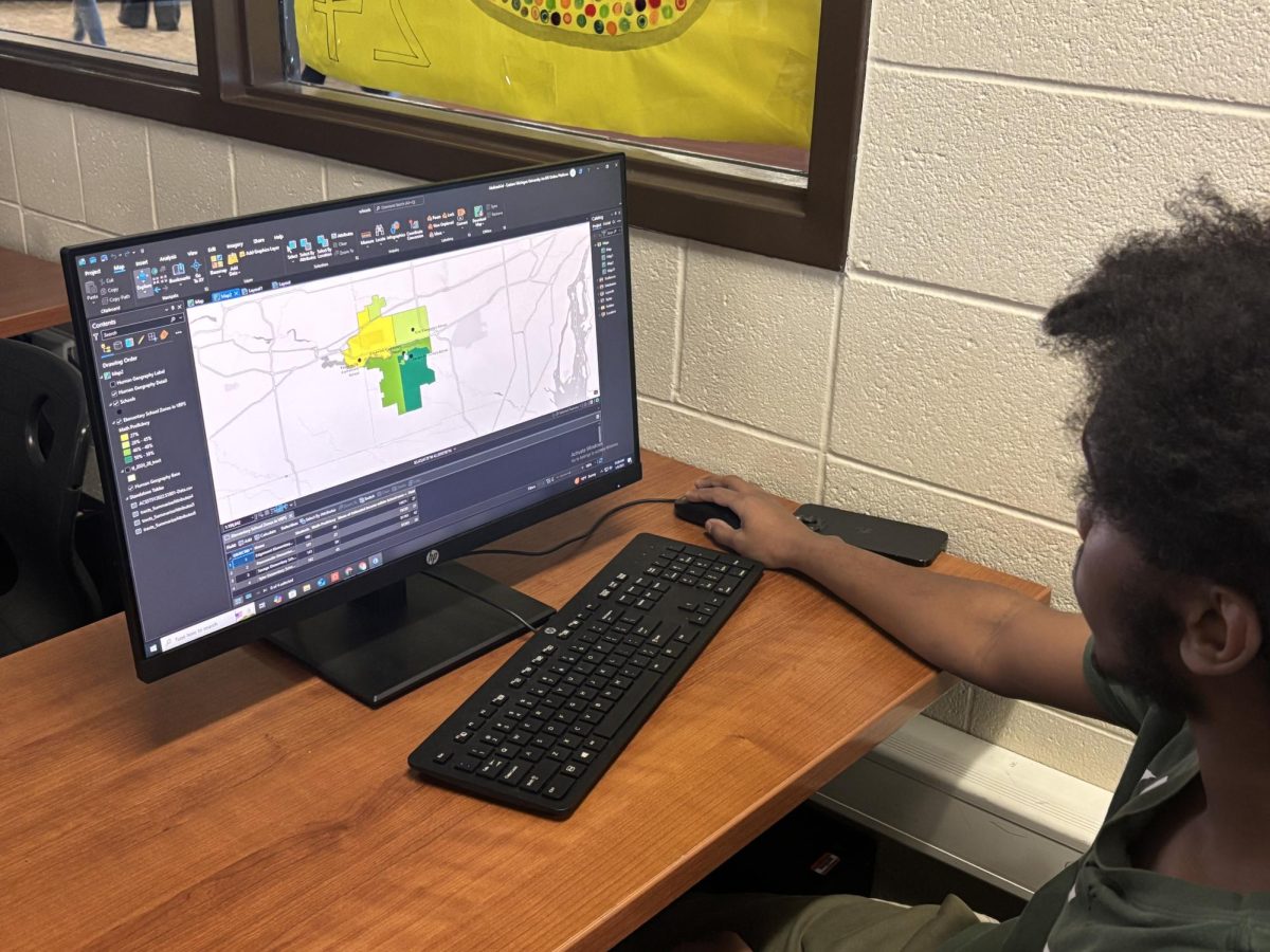 Senior Abdirashiid Ibrahin in the GIS room finishing the final touches on his and his group's group project . The students were tasked to make projects combining two pieces of data together into ARC GIS Pro so later they can showcase their project around school. Bailee Robinson, Beneath The Stripes.