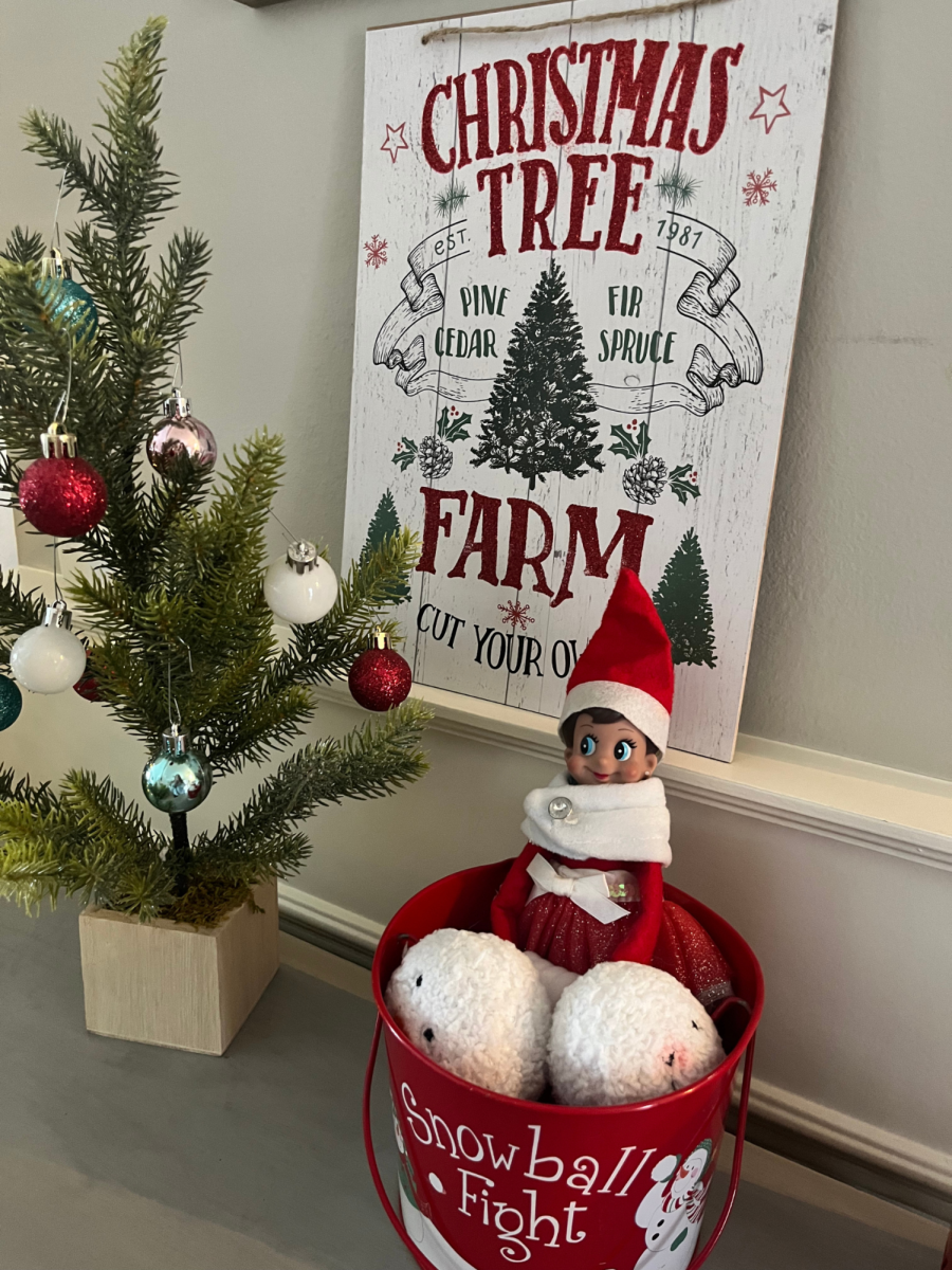 Elf On The Shelf sits among other Christmas decorations. 